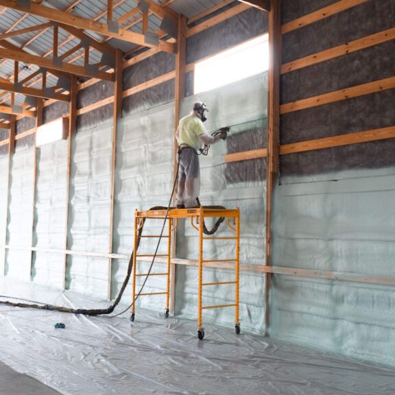 Technician applying spray foam to a wall assembly
